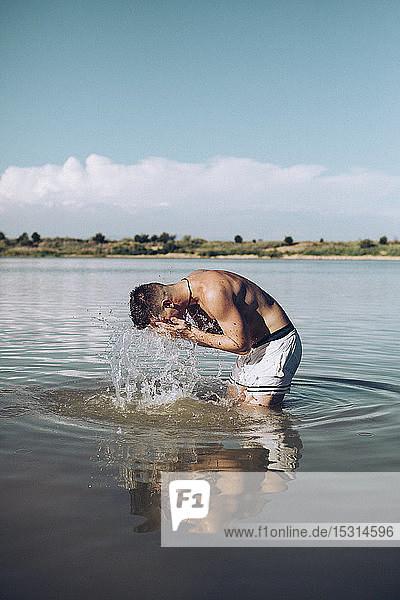 Junger Mann erfrischt sich in einem See