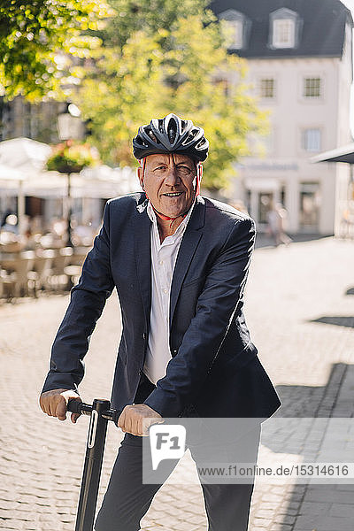 Porträt eines lächelnden älteren Mannes mit E-Scooter in der Stadt