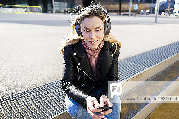 Porträt einer jungen Frau  die mit Smartphone und Kopfhörern Musik hört  Barcelona  Spanien