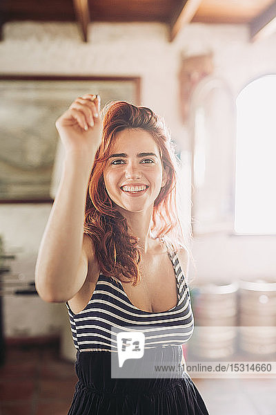 Portrait of happy young woman playing darts in a sports bar