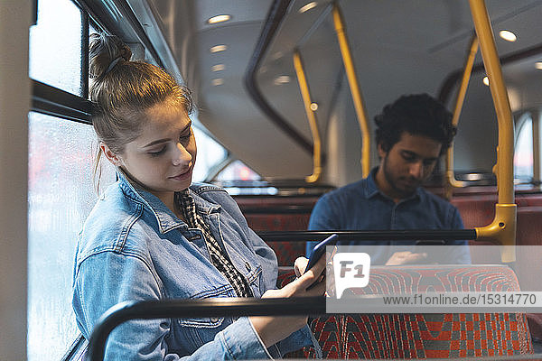 Mann und Frau benutzen Mobiltelefone im Bus