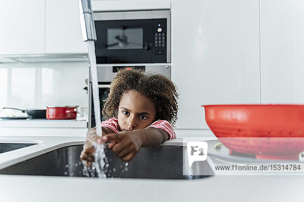 Girl washing her hands at kitchen sink