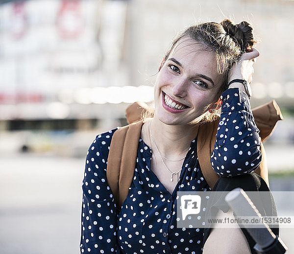 Porträt einer lächelnden jungen Frau mit Roller