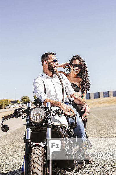 Portrait of laughing couple sitting on motorbike