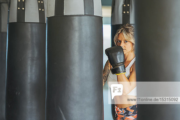 Porträt einer Frau mit Boxhandschuhen beim Sandsack in der Turnhalle