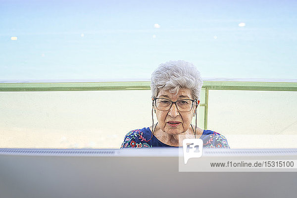 Ältere Frau benutzt Computer auf der Terrasse