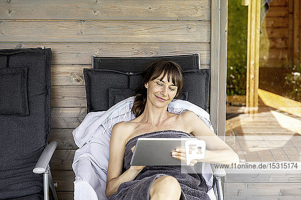 Frau entspannt sich in einer Lounge außerhalb der Sauna mit Tabletten