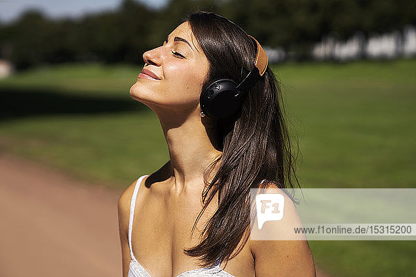 Porträt einer jungen Frau mit Kopfhörern in einem Park im Sommer