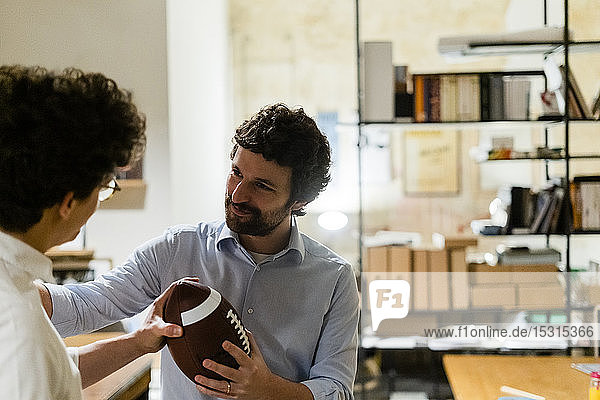 Two businessmen with football in office