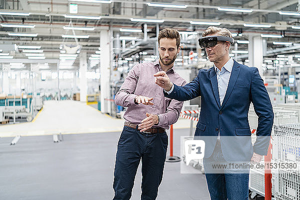 Two businessmen with AR glasses in a modern factory