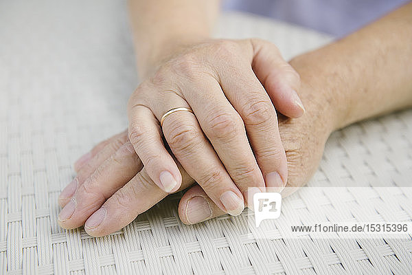 Senior couple sitting at garden table holding hands  close-up
