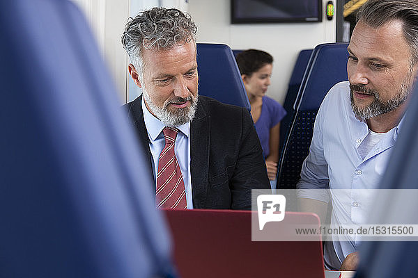 Geschäftsleute  die mit dem Zug reisen und am Laptop arbeiten