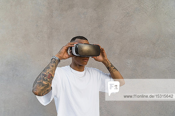 Tattooed young man using Virtual Reality Glasses looking up