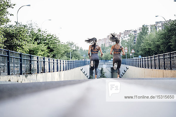 Oberflächenniveau von zwei sportlichen Zwillingsschwestern  die auf einer Straße laufen