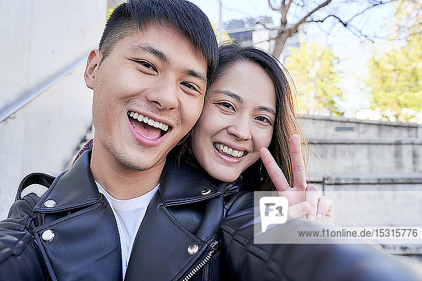 Portrait of happy young couple making victory sign