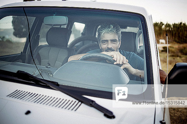 Smiling mature man sitting in his off-road vehicle