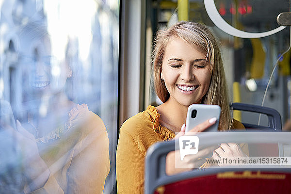 Smiling young woman using smartphone in a tram
