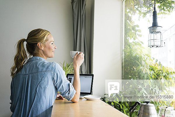 Blonde Frau sitzt im Café  benutzt Laptop  trinkt Kaffee
