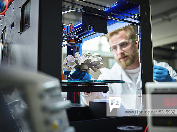 Techniker mit Turbinenrad  das in einem 3D-Drucker gedruckt wird