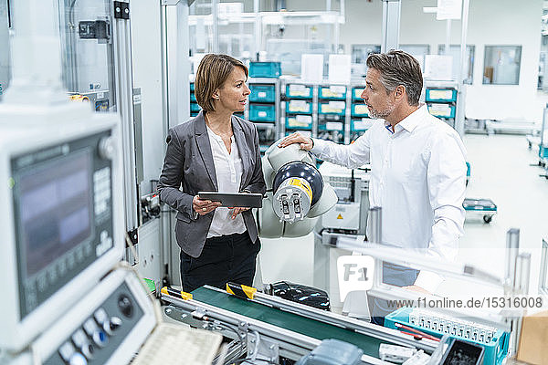 Businesswoman and man talking at assembly robot in a factory