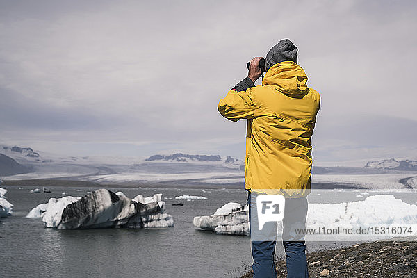 Erwachsener Mann beobachtet den Vatnajokull-Gletscher mit dem Fernglas  Island