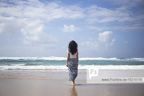 Back view of woman standing on the beach looking at the sea  Fuerteventura  Spain