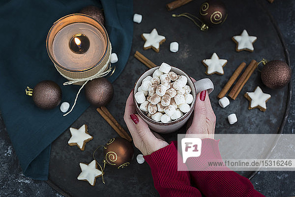 Frauenhände halten zur Weihnachtszeit eine Tasse heiße Schokolade mit Marshmellows