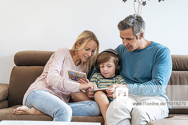 Family on couch at home with boy listening to music with headphones