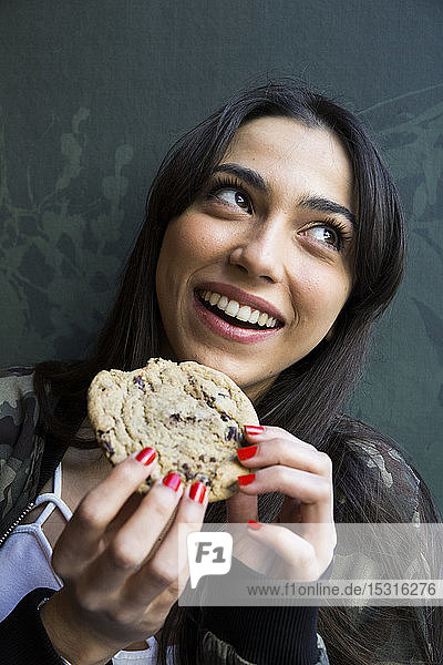Lächelnde Frau schaut zur Seite und isst einen Keks