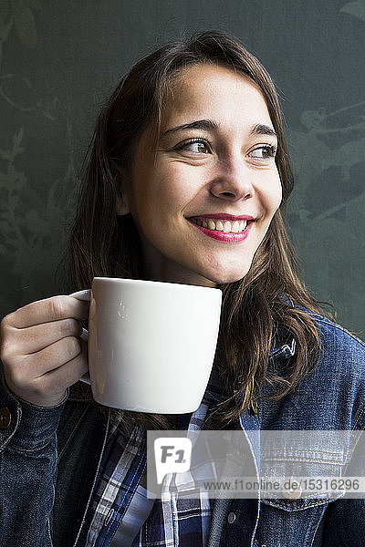 Young woman sitting in cafe with cup of coffee and looking sideways