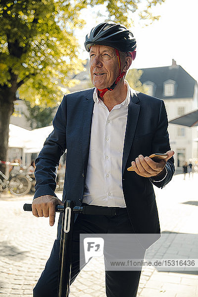 Älterer Mann mit E-Scooter in der Stadt mit Smartphone