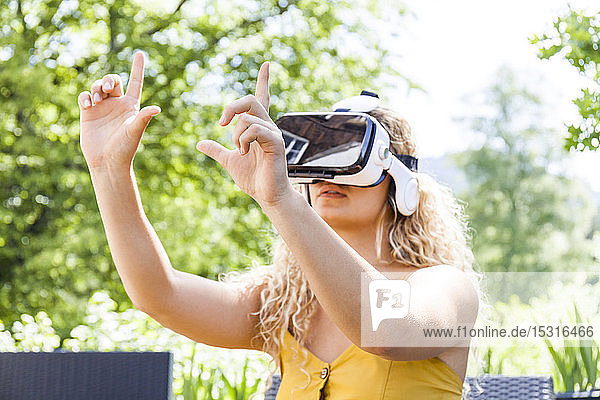 Junge blonde Frau mit Virtual-Reality-Brille im Freien