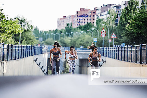Drei sportliche junge Frauen laufen auf einer Straße