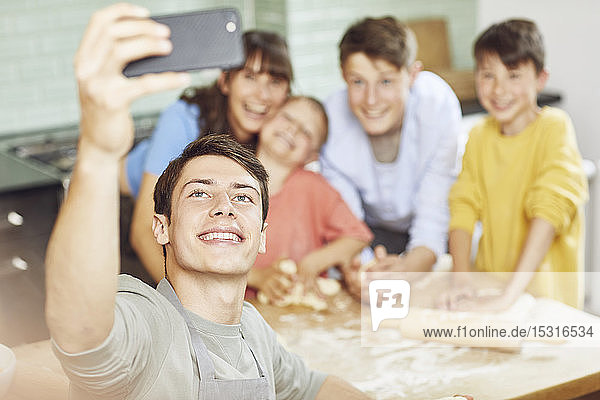 Einer  der Fotos von seiner Mutter und seinen Brüdern macht  die zu Hause Pizza zubereiten