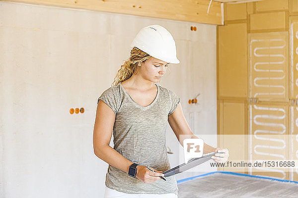 Junge Frau prüft den Bau eines neuen Holzhauses