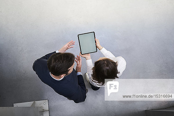 Draufsicht eines Geschäftsmannes und einer Frau mit Tablette im Gespräch in einer Fabrik