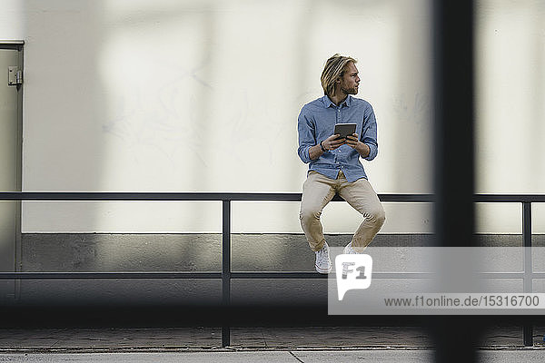 Young man with tablet in the city looking around