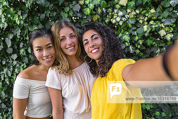 Porträt von drei lächelnden jungen Frauen  die ein Selfie
