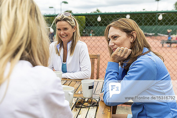 Gruppe von Frauen  die sich nach einem Spiel in einem Cafe im Tennisclub unterhalten