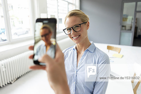 Smartphone picture of young businesswoman in office