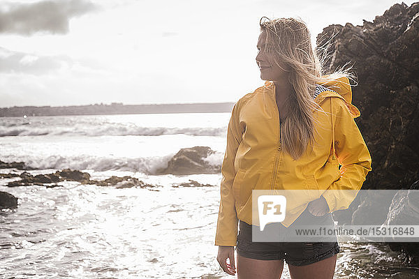 Woman wearing yellow rain jacket standing at the beach