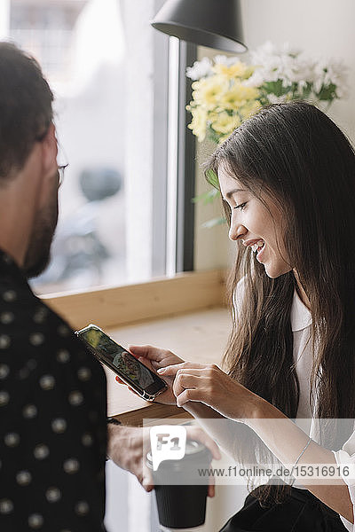 Young couple with disposable cup and smartphone in a cafe