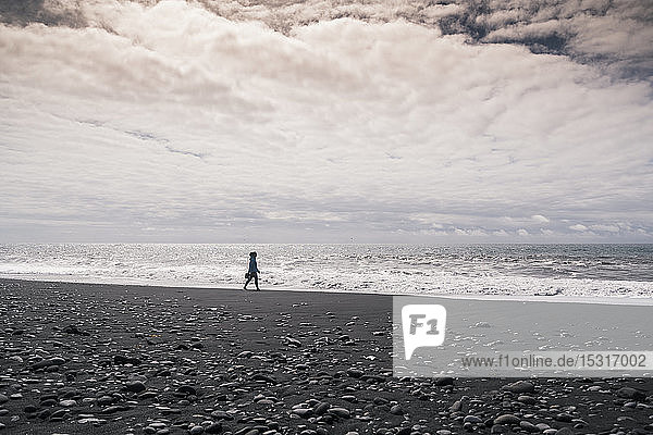Young woman walking on barefoot on a lava beach in Iceland