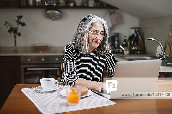 Portrait of senior woman using laptop at breakfast table