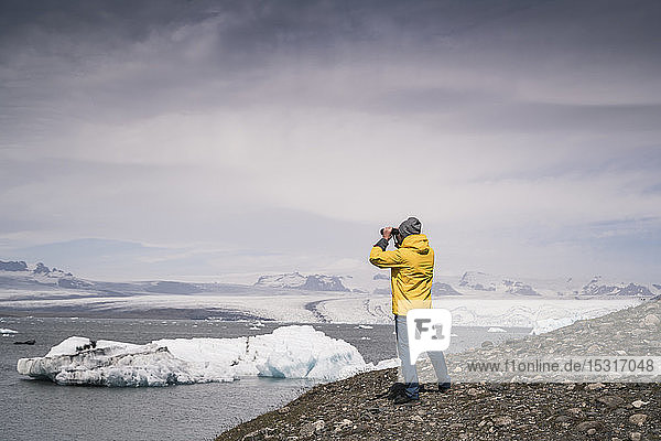 Mature man watching Vatnajokull glacier with binoculars  Iceland