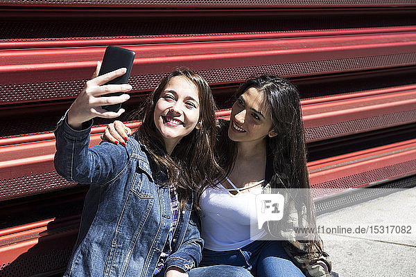 Young women sitting on ground and posing for selfie in Madrid  Spain