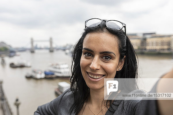 Porträt einer Frau  die sich in der Stadt ein Selfie gönnt  mit der Tower Bridge im Hintergrund  London  UK