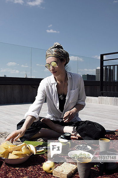 Stilvolle Frau mit Sonnenbrille beim gesunden Essen auf dem Dach
