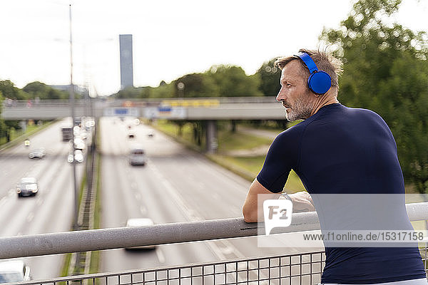 Sporty man standing on a bridge wearing headphones