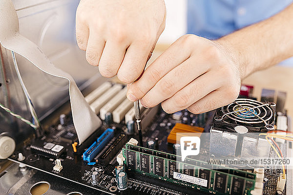 Nahaufnahme eines Technikers  der einen Desktop-Computer mit einem Schraubenzieher repariert